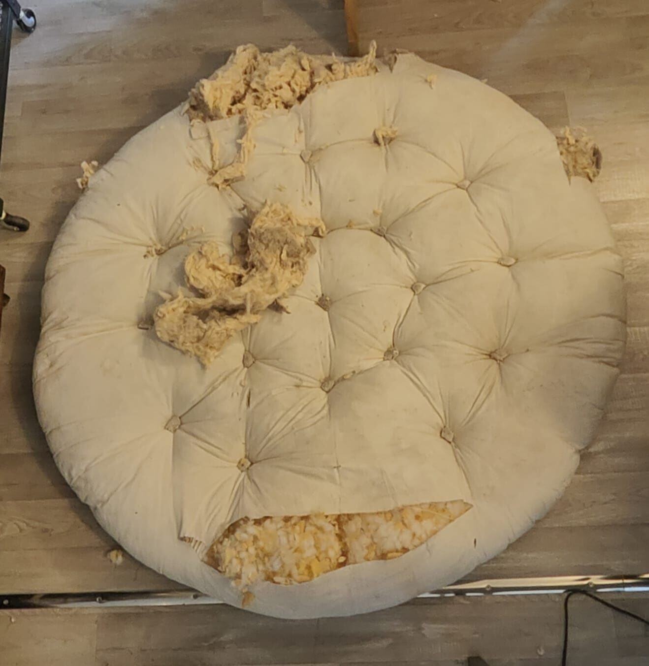 Coussin de sol rond capitonné, éventré, garnissage qui dépasse