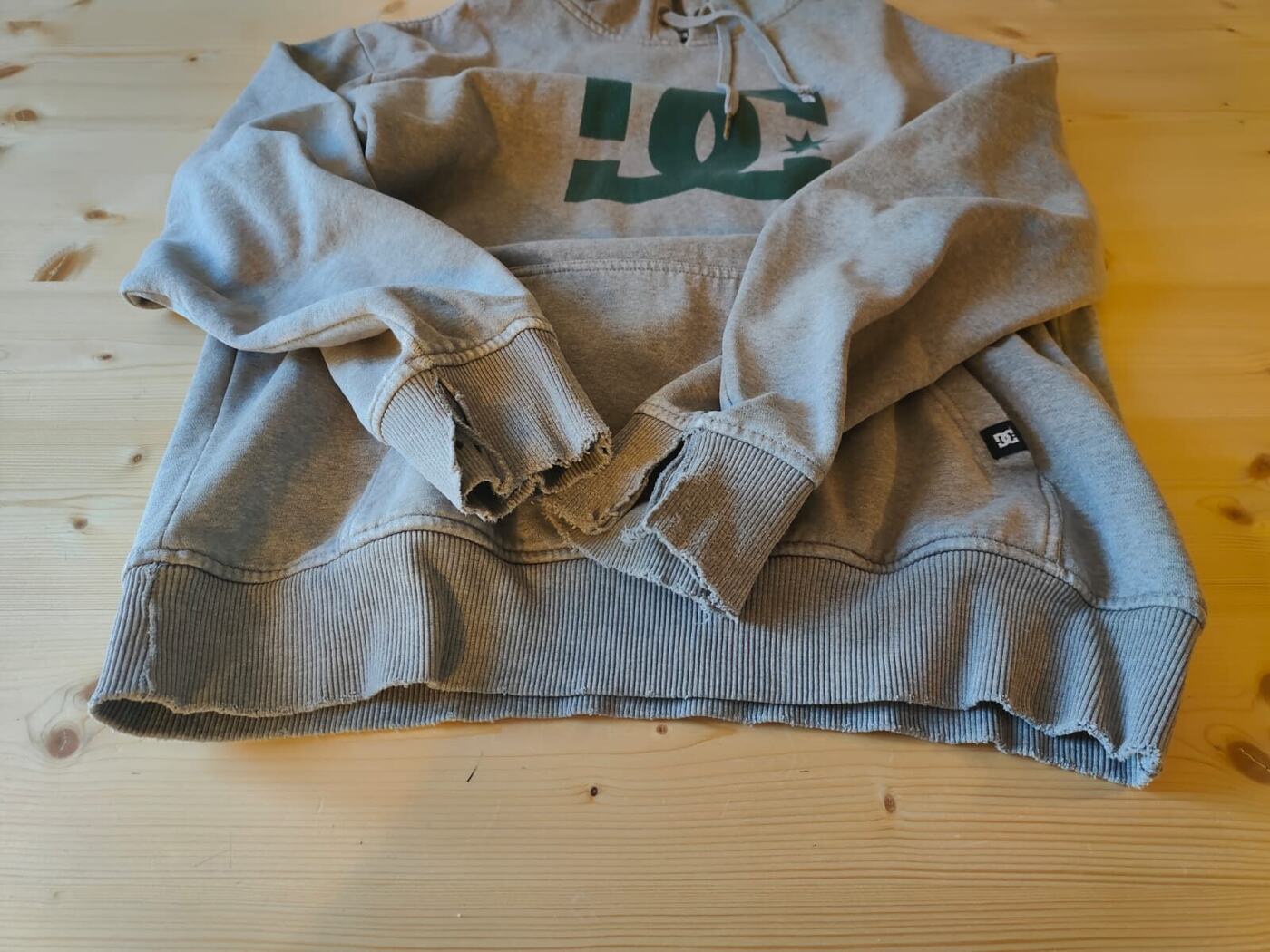 Sweat à capuche gris aux poignets et à la bordure effilochés